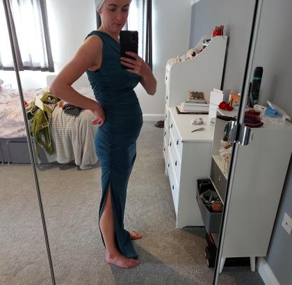 Lucy standing in front of the mirror showing her bloated stomach 