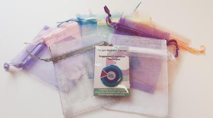 A photo of our pin badge wedding favour with some colourful organza bags