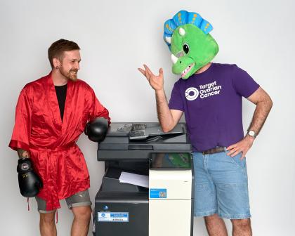 Two people in fancy dress costumes by an office printer