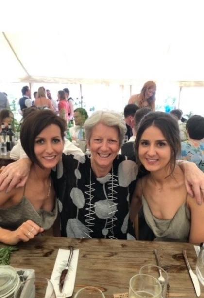 Gaby and Chloe sitting at a table outside with their mum in the middle, all smiling