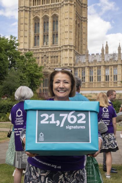 Annwen standing outside the Houses of Parliament holding a box of signatures