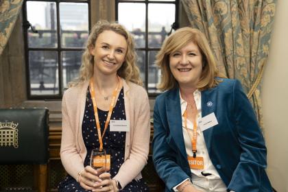 Charlotte and Joanne, two TOC campaigners sitting in Westminster Parliament at our reception event smiling towards the camera