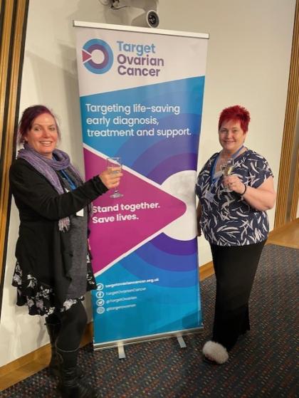 Lorraine at Scottish parliament standing next to a Target Ovarian Cancer pull up banner