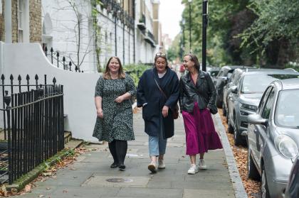 Three women walking down the street together all chatting a smiling