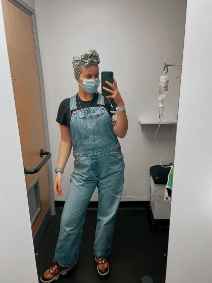 Claire in hospital taking a selfie in a mirror wearing a headscarf and dungarees