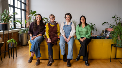 A photo of four women who have all had an ovarian cancer diagnosis sitting on the back of a sofa together all smiling