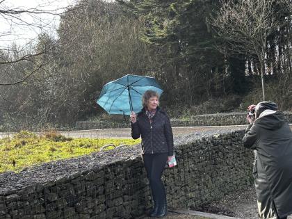 Gill standing in the woods holding a teal umbrella