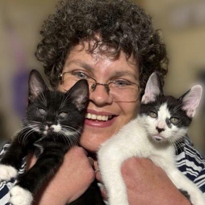 Claire smiles as she holds two of her cats.