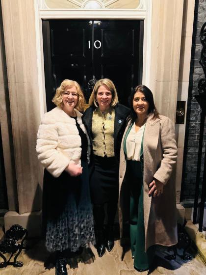 Three smartly dressed women standing in front of the door to 10 Downing Street.