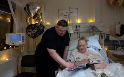 Edd sits next to Sophie on a hospital bed surrounded by wedding balloons as they got married. 
